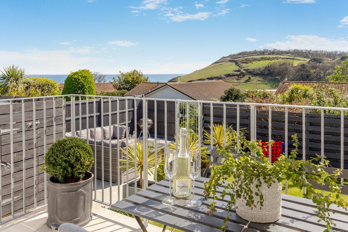 Eine Terrasse mit Esstisch, bequemen Sitzmöbeln und Blick ins Grüne.