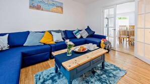 Un salon avec un canapé bleu, une table basse en bois et un tableau accroché au mur.