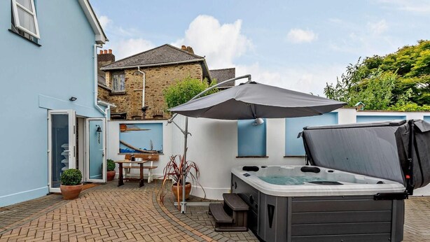Une terrasse avec un jacuzzi, une table, des chaises et une plante en pot.