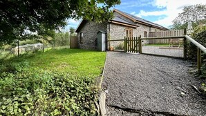 A stone building with a gravel driveway and a wooden fence. - 1 Bed in Aberystwyth (oc-83551) (Llanilar)