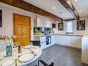 A modern kitchen with white cabinetry, a marble countertop, and a dining area with a round table set for four. - 1 Bed in Milnthorpe (oc-83560) (Heversham)