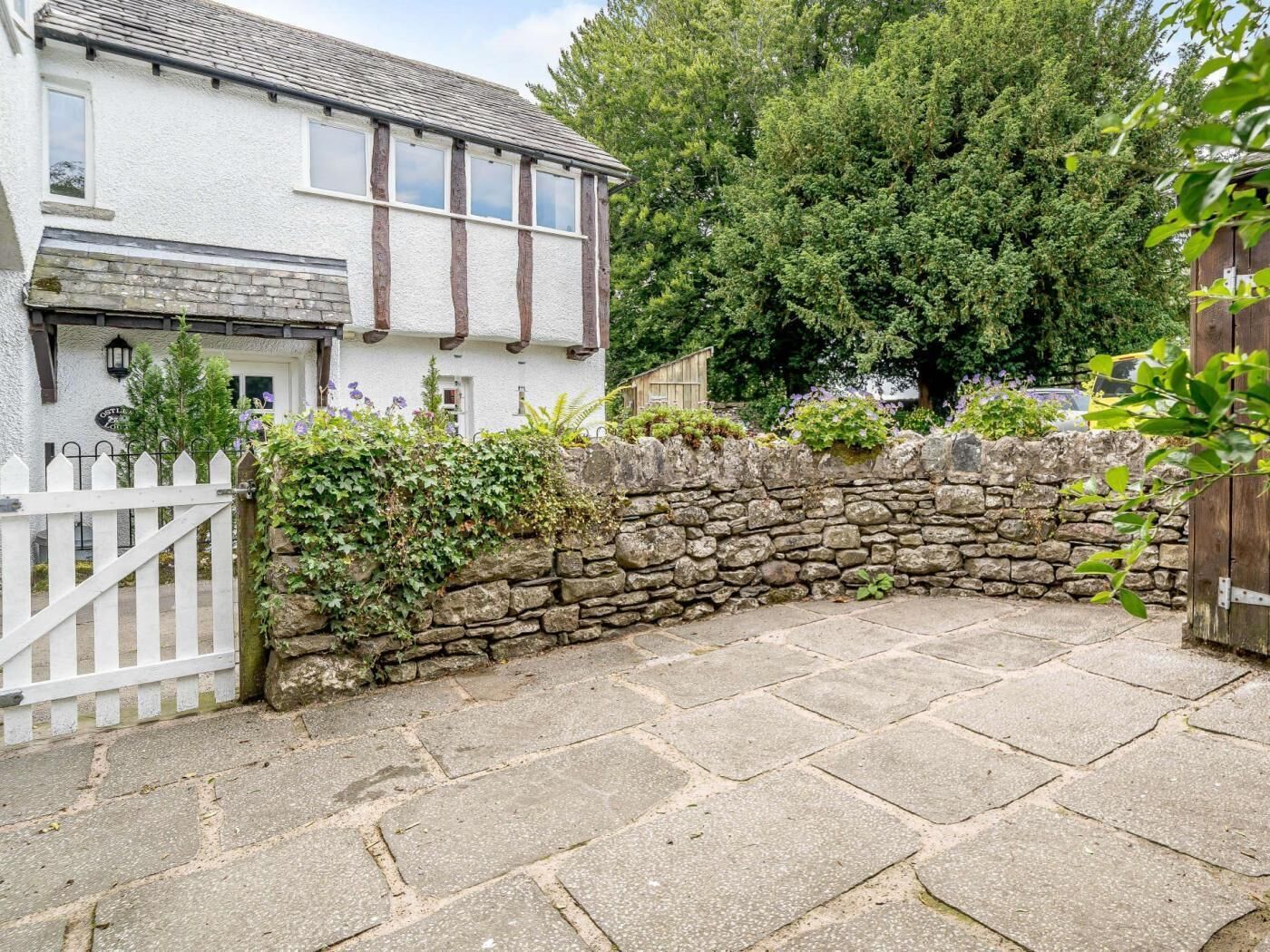 A traditional white house with a stone wall and a white picket fence.