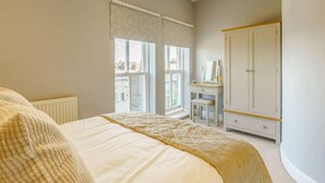 A bedroom with a large bed, a dresser, a vanity with a mirror, and a window with blinds. - 2 Bed in Ripon (oc-83763) (Ripon)