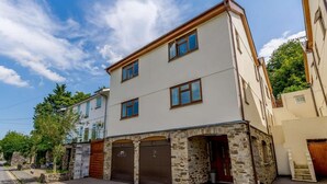 A corner building with a stone facade, a garage, and a visible entrance. - 4 Bed in Okehampton (oc-83785) (Okehampton)
