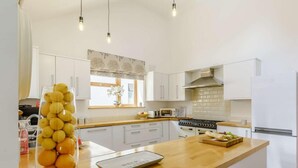 A modern kitchen with white cabinets, a wooden countertop, a built-in oven, and a refrigerator. - 4 Bed in Okehampton (oc-83785) (Okehampton)