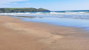 A beach with waves, a clear sky, and distant hills. - 3 Bed in Torpoint (oc-83792) (Millbrook)