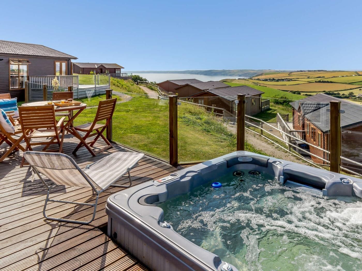 Un bain à remous sur une terrasse offrant une vue sur la mer et les collines.