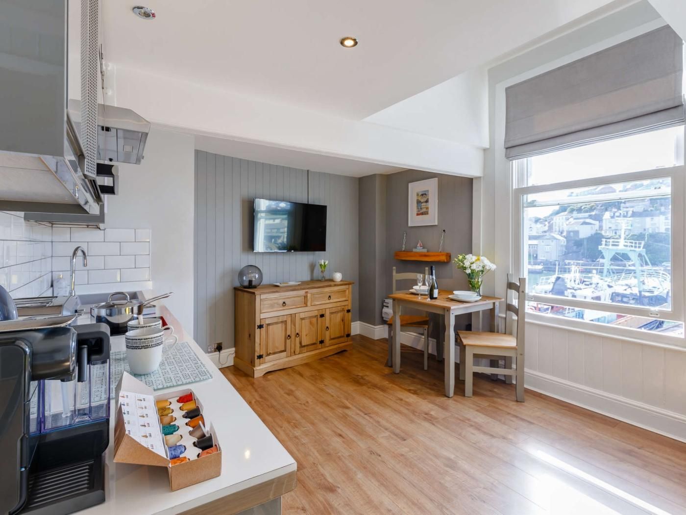 A modern kitchen with a built-in espresso machine, wooden cabinetry, and a dining area with a view of the harbor.
