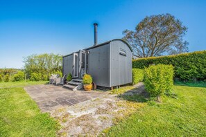 A metal shed with a chimney, a small outdoor seating area, and a paved entrance. - 1 Bed in Narberth (oc-83862) (Whitland)