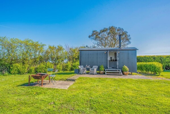 A small, single-story building with a kitchen area visible through an open door, surrounded by a grassy yard and a hedge. - 1 Bed in Narberth (oc-83862) (Whitland)
