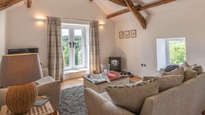 Un salon chaleureux avec un haut plafond, une cheminée, un canapé, une table basse et un téléviseur.