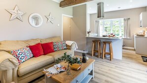 Ein modernes Wohnzimmer mit Sofa, Couchtisch und einer Küchenzeile mit Barhocker.