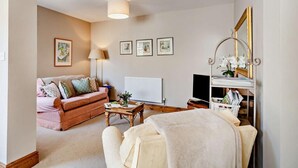Ein gemütliches Wohnzimmer mit Sofa, Couchtisch, Lampe, Heizkörper und Fernseher.