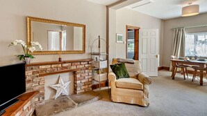 Ein Wohnzimmer mit Kamin, Fernseher, einer Couch und einem Essbereich mit Tisch und Stühlen.