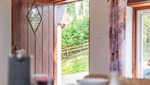 Una stanza con una porta in legno, vista su un giardino e un tavolo con diversi oggetti.