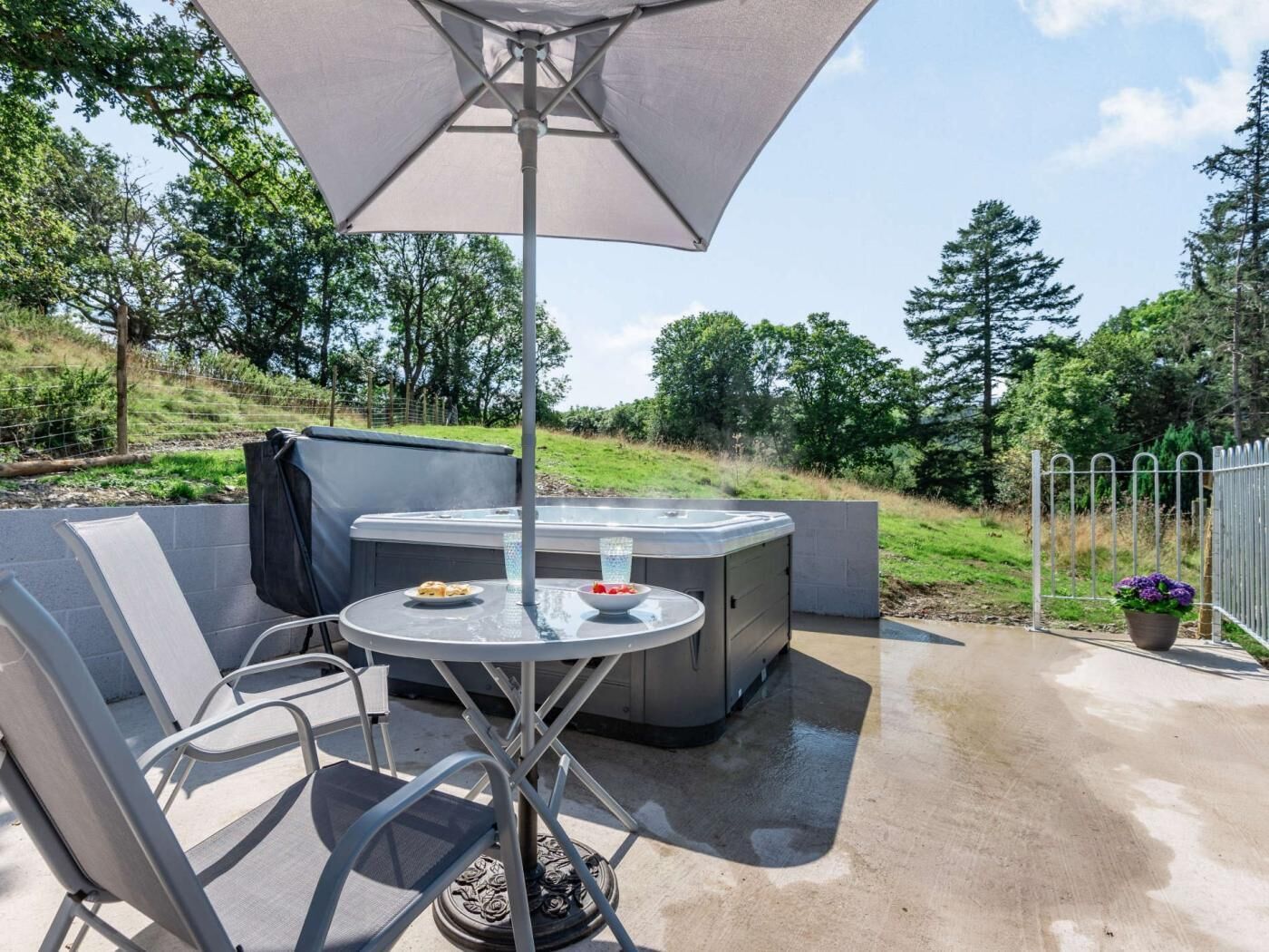 An outdoor seating area with a table, chairs, a hot tub, and a large umbrella.