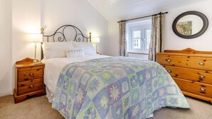 A bedroom with a bed, bedside tables, a dresser, a window with curtains, and a wall-mounted mirror. - 2 Bed in Bakewell (oc-85314) (Ashford in the Water)