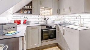 A modern kitchen with grey cabinets, a built-in oven, a sink, and a red toaster. - 2 Bed in Bakewell (oc-85314) (Ashford in the Water)