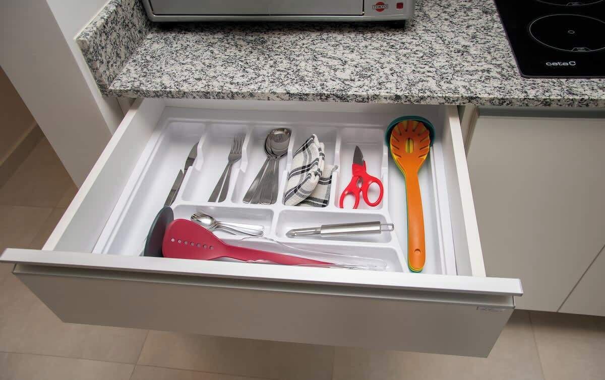 Un tiroir de cuisine contenant des ustensiles et une spatule.