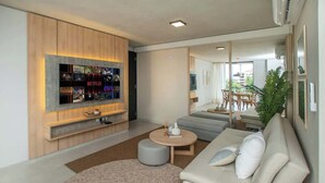 A modern living room with a flat-screen TV, a sofa, a coffee table, and a large mirror. - Corporate Stays Insignia City - A43 (Asunción)