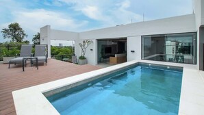 A modern outdoor swimming pool with a wooden deck, glass doors, and a view of the city. - Corporate Stays Insignia City - A43 (Asunción)
