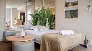 A modern hotel room with a bed, a round table, a seating area, and a view of the beach. - Corporate Stays Insignia City - A43 (Asunción)