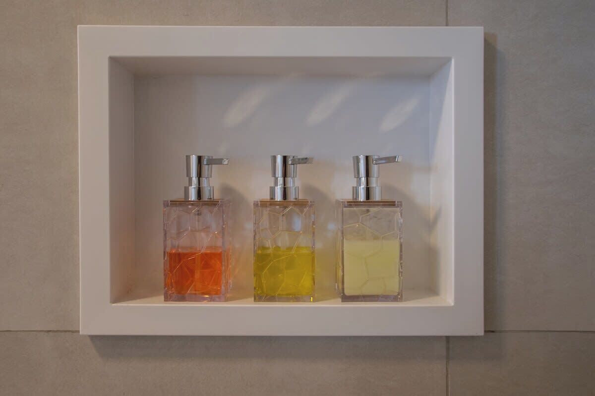 A white shelf with three transparent dispensers containing different colored liquids.