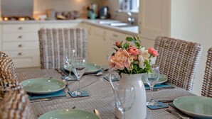 En spiseplads med et bord dækket til to, en vase med blomster og fletstole.