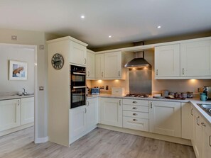 A modern kitchen with white cabinets, a built-in oven, a gas stove, and a stainless steel range hood. - 4 Bed in Bideford (oc-85367) (Westward Ho!)