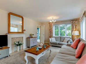 A living room with a fireplace, sofa, coffee table, and a television. - 4 Bed in Bideford (oc-85367) (Westward Ho!)