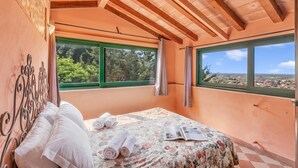 Ein Schlafzimmer mit Bett, Fenster und Blick ins Freie.