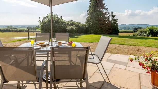 Ein Essbereich im Freien mit Tisch, Stühlen und Sonnenschirm.