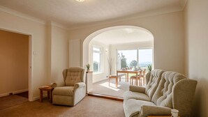 Ein geräumiges Wohnzimmer mit Sofa, Sessel und Essbereich.