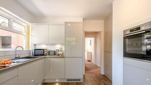 Eine moderne Küche mit weißen Schränken, einer Mikrowelle, einem Toaster und einem Kühlschrank.