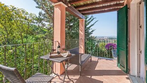 Ein Balkon mit Tisch und Stühlen, einer Pergola und Blick auf Grünflächen und eine entfernte Landschaft.