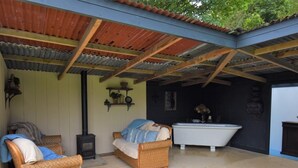 A covered outdoor area with wicker furniture, a fireplace, and a bathtub. - 1 Bed in Llandysul (oc-85415) (Rhydowen)