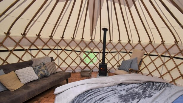 A yurt interior with a bed, a sofa, and a small heater. - 1 Bed in Llandysul (oc-85415) (Rhydowen)