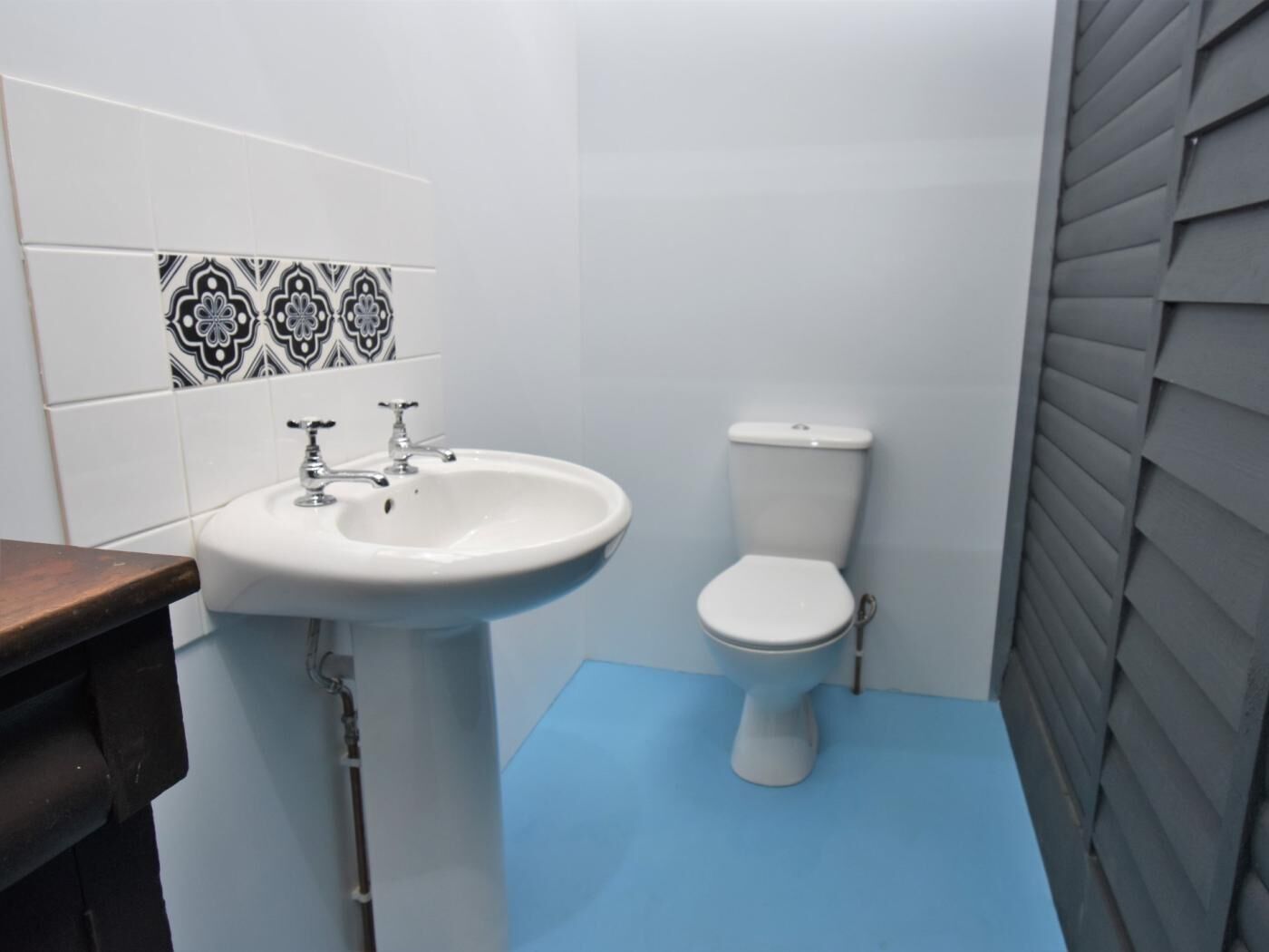 A bathroom with a white sink, a toilet, and patterned tiles on the wall.