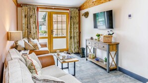 Ett mysigt vardagsrum med en soffa, ett soffbord, en tv som är monterad på väggen och ett träskåp.