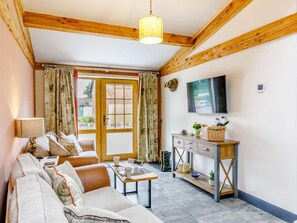 A cozy living room with a sofa, a coffee table, a TV mounted on the wall, and a wooden cabinet. - 2 Bed in Ripon (oc-85510) (Masham)