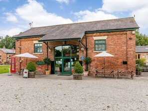 A brick building with a reception area, outdoor seating, and a red telephone booth. - 2 Bed in Ripon (oc-85510) (Masham)