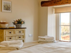 Ein Schlafzimmer mit Bett, Schminktisch, Fenster mit Aussicht und einem Wandbild.