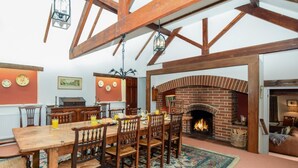 Ein Essbereich mit Kamin aus Backstein, Holzmöbeln und einem gemusterten Teppich.
