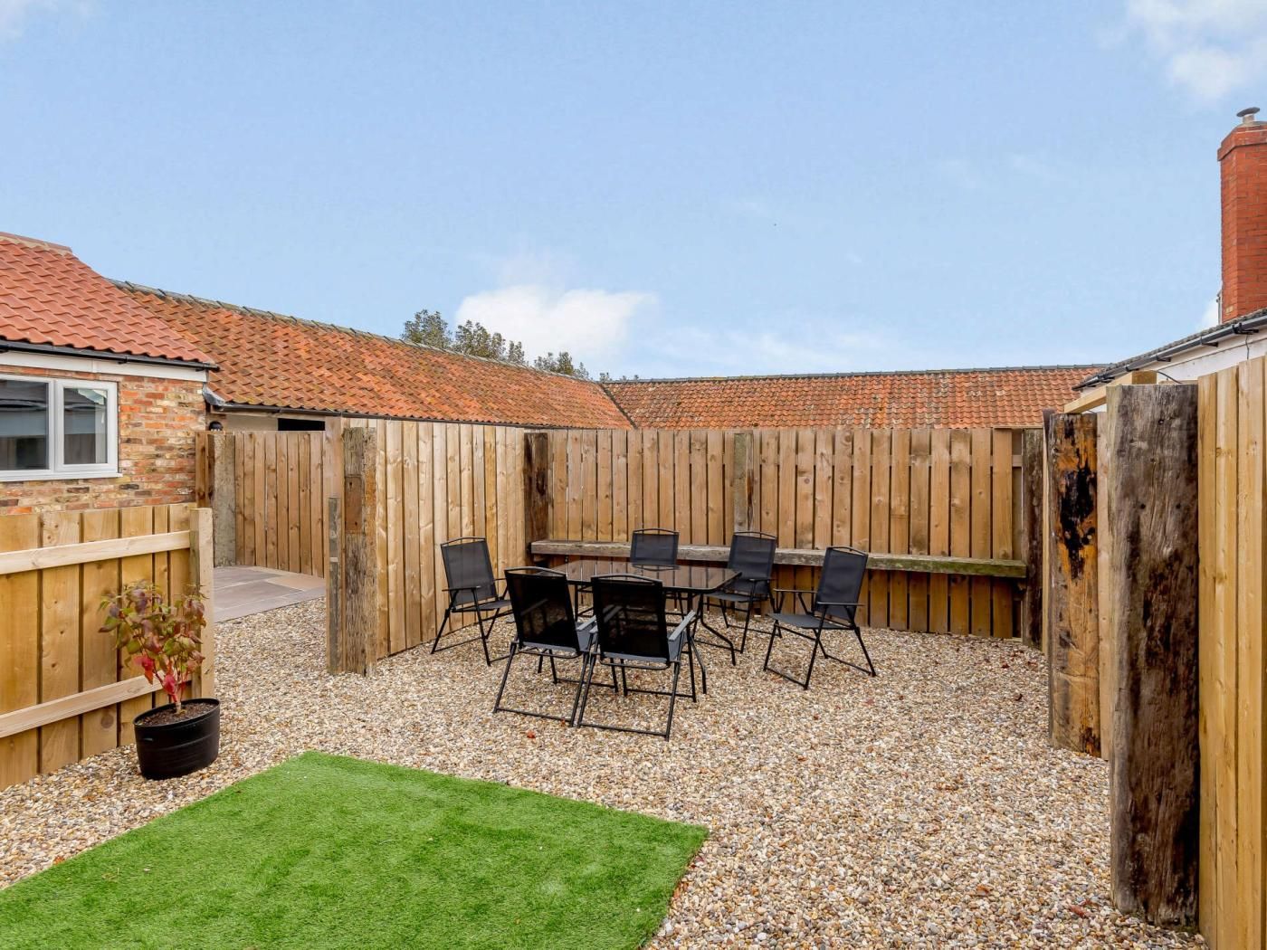 A backyard with a barbecue area, a table, and chairs.