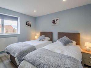 Ein Schlafzimmer mit zwei Betten, einem Fenster und Bildern an den Wänden.