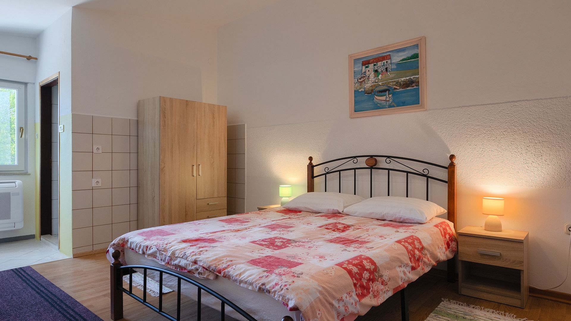 A bedroom with a bed, bedside tables, a wardrobe, and a painting on the wall.