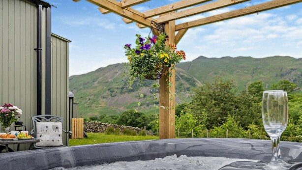 A hot tub with a glass of wine, a wooden pergola with flowers, and a mountain view. - 1 Bed in Penrith (oc-85531) (Deepdale)