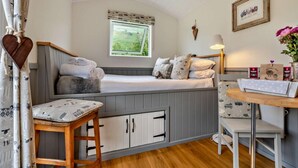 A cozy room with a bed, a small table, a window with a view, and a wall-mounted lamp. - 1 Bed in Penrith (oc-85531) (Deepdale)
