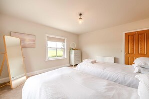 Ein Schlafzimmer mit zwei Betten, einem Schminktisch, einem Fenster und einer Tür.