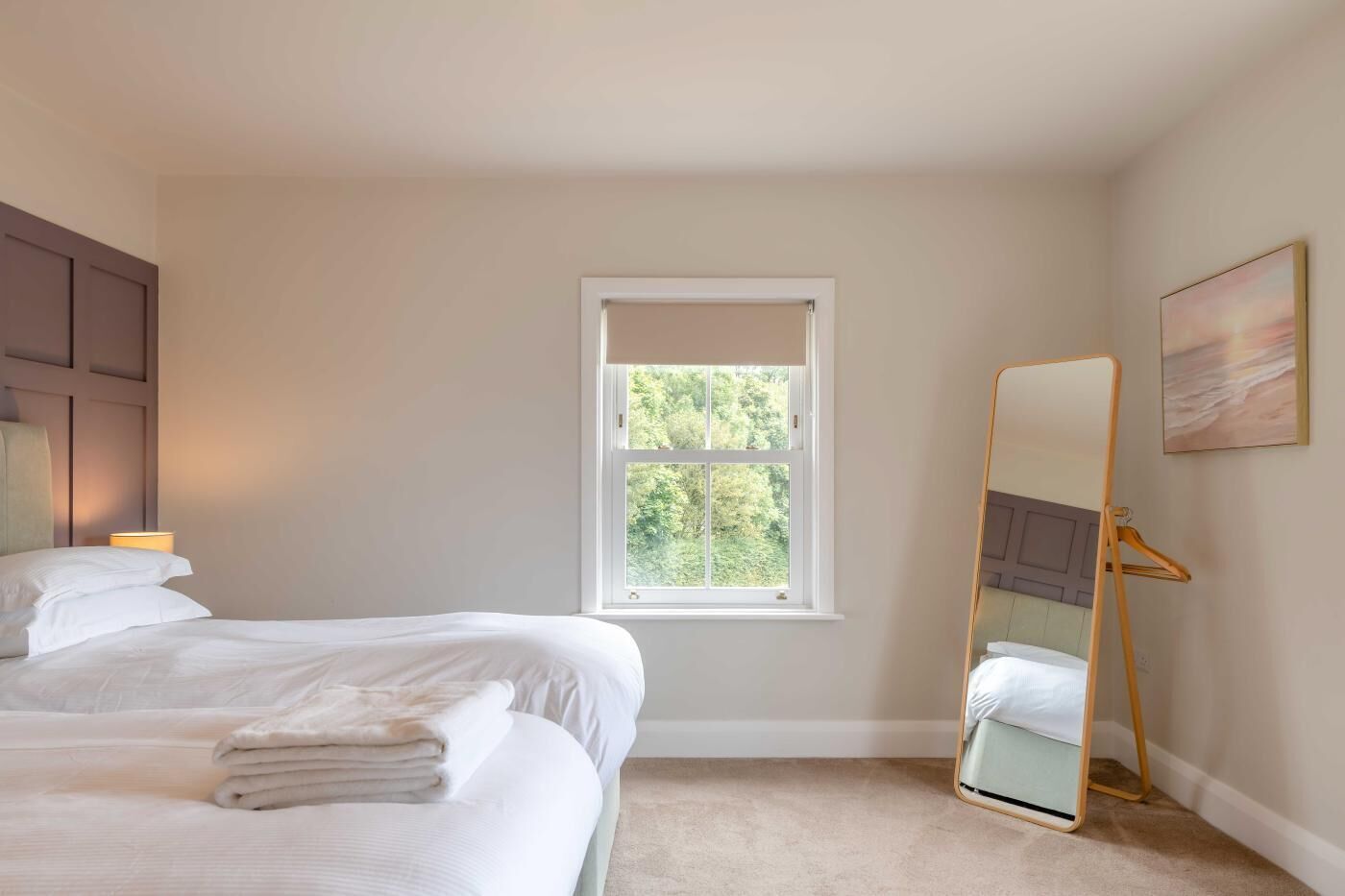 Une chambre à coucher avec un lit, une fenêtre, une table de chevet et un miroir.